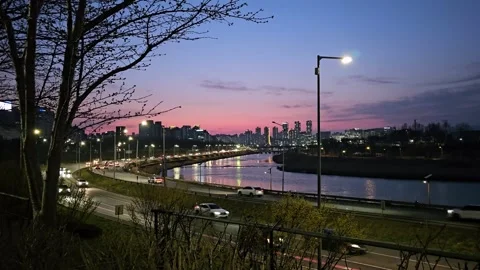 Evening Traffic Flow Along Riverside Road with City Skyline Vídeos de archivo 331297236
