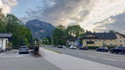 Evening traffic passes through an Austrian alpine town, with roadside Video stock 339070675