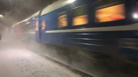 Evening train arrives at station. Snowfall complicates transportation of passeng Stock Footage 230959307