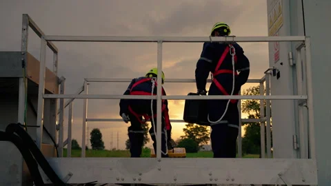 In the evening, Two maintenance engineers in safety gear working at height Stock Footage 165046522