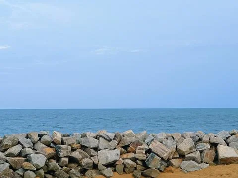 Evening view of the beach in front of large rocks used as wave breakers Stock Photos