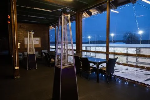 Evening view from inside a dark cafe with a pyramid patio heater, looking out Stock Photos