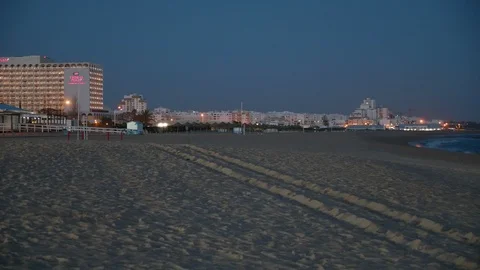 Evening view looking across the sandy beach towards hotels in the distance Stock Footage 106497543