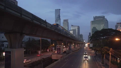Evening view of skytrain passing above Sathon Road in Bangkok Stock Footage 99132256
