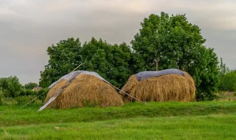 Evening village landscape with a haystack on the background of the sunset Stock Photos