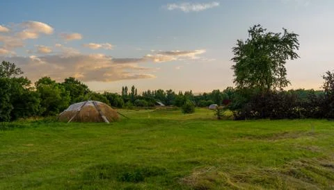 Evening village landscape with a haystack on the background of the sunset Stock Photos