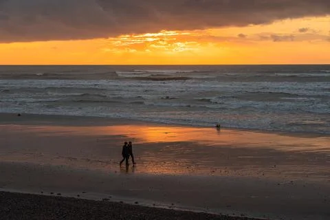 Evening walk on the beach at dramatic sunset Stock Photos