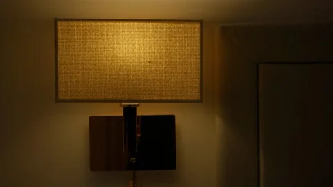 Evening wall lamp casting warm light in bedroom Stock Footage 306331226