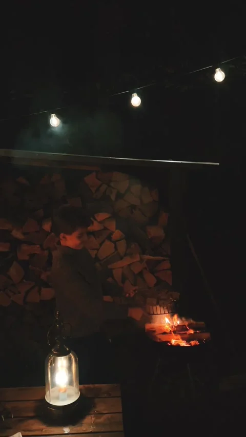 Evening by the Warm Fire with Lanterns and Neatly Stacked Wood for Comfort Stock Footage 291725642