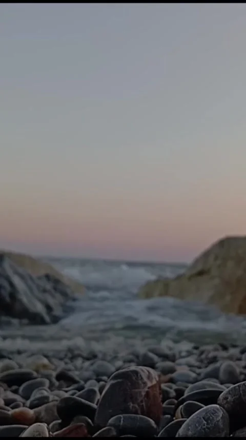 Evening Waves on a Pebble Beach Under a Soft Pastel Sky Stock Footage 338185344
