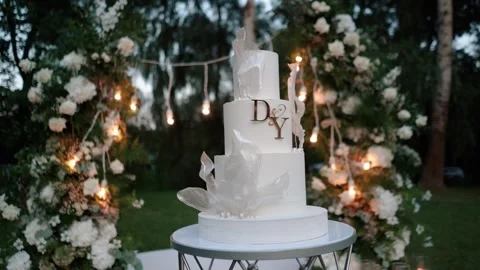 Evening wedding arch of white flowers outdoors. Large white cake with cream Stock Footage 282856745