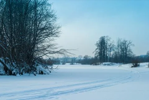 The evening at the winter forest river wih ski track, in cloudy day at sunset Stock Photos