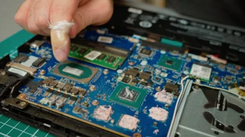 Evenly distributing thermal paste on processor during laptop repair. Ensuring Stock Footage 303153765