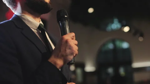 Event host gesturing hands while giving speech in microphone Video stock 250084672