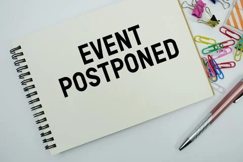 Event Postponed text message written on notepad with stationery flat lay on.. Stock Photos