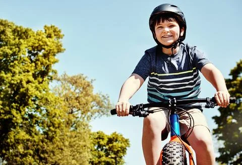 Every pedal pushes the fun even further. a young boy riding his bicycle through Stock Photos