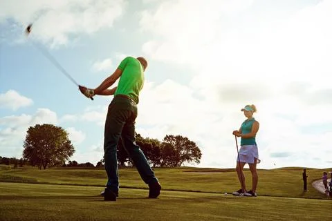 Every swing makes him a better player. a couple playing golf together on a Stock Photos