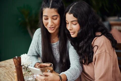 Every time we share, we connect. young sisters using a smartphone together at a Fotos Stock