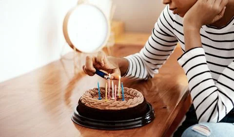 Everybody forgot my birthday. a woman lighting candles on a birthday cake at Stock Photos