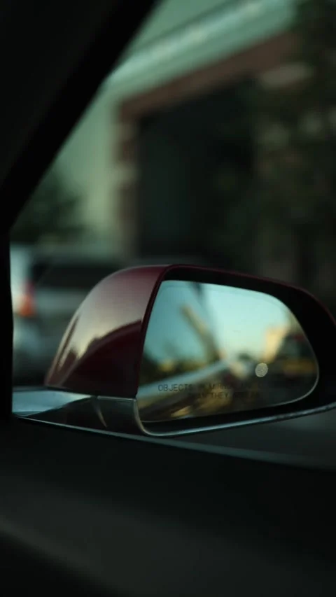 Everyday city driving captured through a reflective rearview mirror Stock Footage 346545822