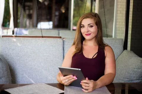 Everyday look. Plus size model. Beautiful young woman with a tablet in a Stock Photos