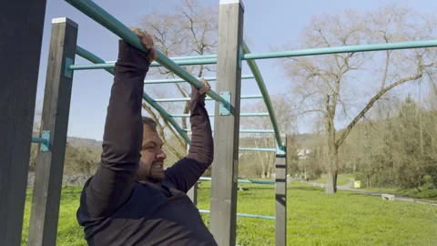 Everyday Struggle: Man Attempts Pull-Ups at Park Stock Footage 263779267