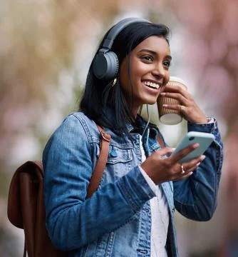 Everything is going my way today. a young woman wearing headphones while using Stock Photos