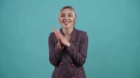 The evil blonde, clasping her hands together, playing conspiratorially with her Stock Footage 153218805