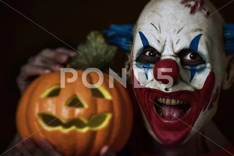 Evil clown with a carved pumpkin Stock Photos