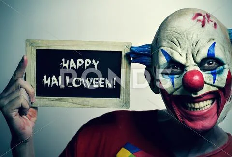 Evil clown with a chalkboard with the text happy Halloween Stock Photos