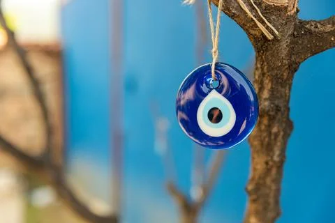 Evil eye bead hanging on the tree, space for text with blue background Stock Photos