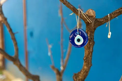 Evil eye bead hanging on the tree, space for text with blue background Stock Photos