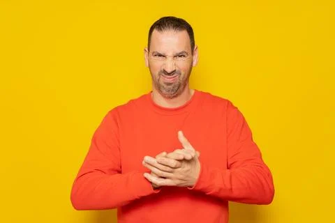 Evil hispanic man rubbing hands on isolated yellow background, person rubbi.. Stock Photos