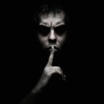Evil man gesturing silence, quiet isolated on black background Stock Photos