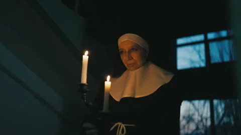 Evil nun ghost holding burning candles and walking in haunted building at night Stock Footage 257005966
