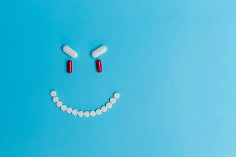 An evil smiling smiley face made of pills on a blue background Stock Photos
