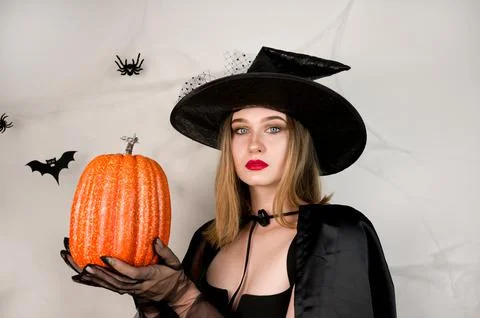 Evil witch in the black with red lips holdin pimpkin. Halloween costume party Stock Photos