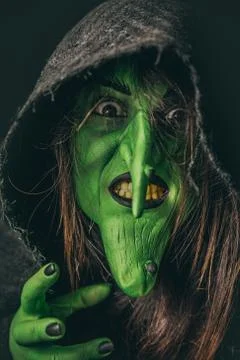 Evil witch casting a curse under her hood Stock Photos