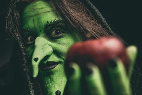 Evil witch looking at camera holding a red apple Stock Photos