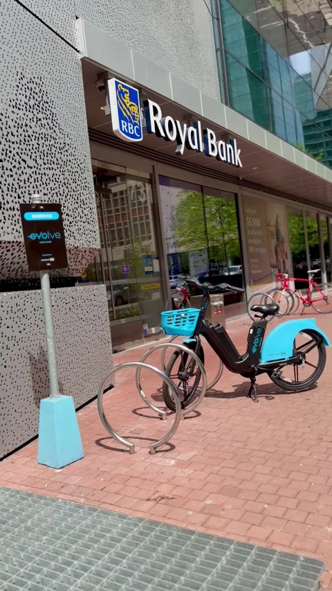 Evolve electric bikes parked at a sharing station on a sunny city sidewalk. 库存影片 334642265