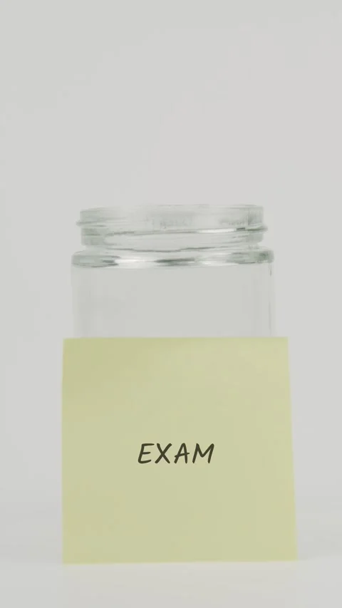 Exam text or word on yellow sticky note attached to glass jar with hand Stock Footage 311728356