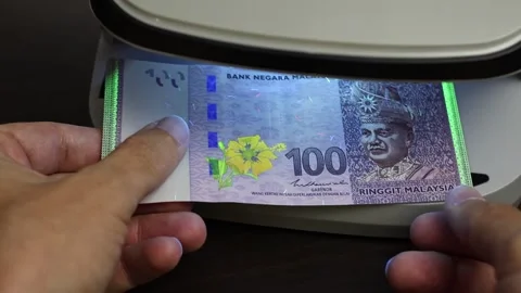 Examination of malaysian ringgit (MYR) cash money with UV counterfeit detector. Stock Footage 312404394