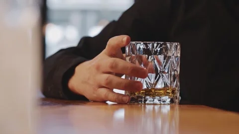Examining the bourbon, the slow motion of a black-shirted hand twirling a glass Stock Footage 242011291