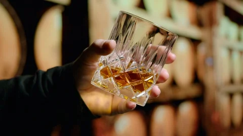 Examining the Bourbon- Slow Motion Hand Swirling Glass of Bourbon Whiskey Stock Footage 126215767