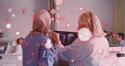 Examining chest X-ray, two clinicians wearing lab coat and scrubs pointing at Stock Photos