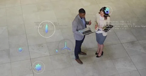 Examining digital overlays, two professionals in suits interacting in lobby with Stock Photos