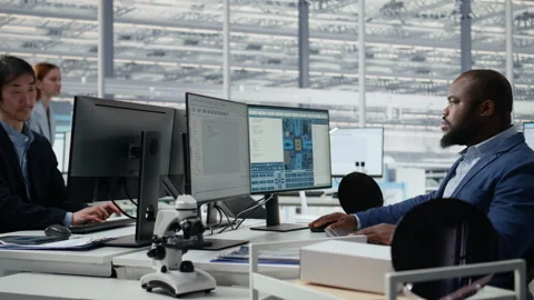 Examining microchip circuit layouts, computer monitor and man in factory office Stock Footage 335877884