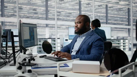 Examining microchip circuit layouts, computer monitor and man in factory office Stock Footage 335880998