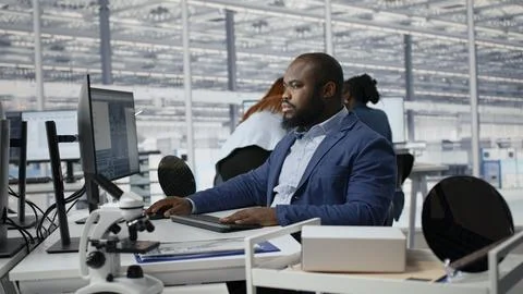 Examining microchip circuit layouts, computer monitor and man in factory office Stock Photos