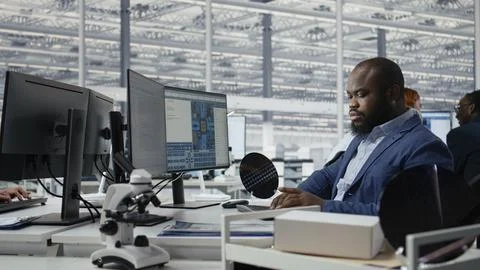 Examining microchip circuit layouts, computer monitor and man in factory office Stock Photos